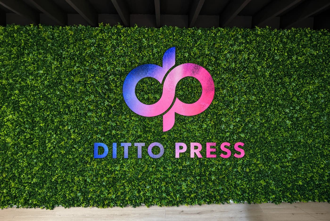 Printed and cut Ditto Press logo mounted on a green wall